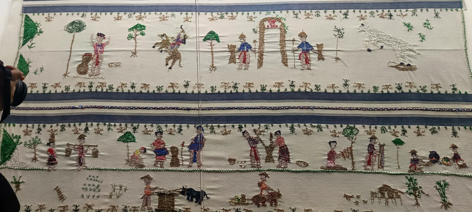 Hand-woven cloth with rows of figures, animals and trees in coloured weft